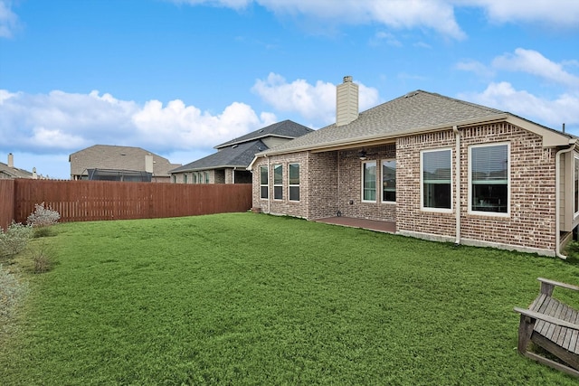 back of property featuring brick siding, a chimney, a shingled roof, and a fenced backyard