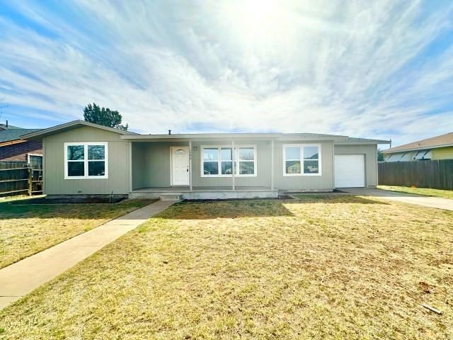 ranch-style home featuring an attached garage, driveway, fence, and a front yard