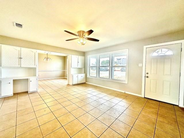 entrance foyer featuring light tile patterned floors, visible vents, a ceiling fan, built in study area, and baseboards