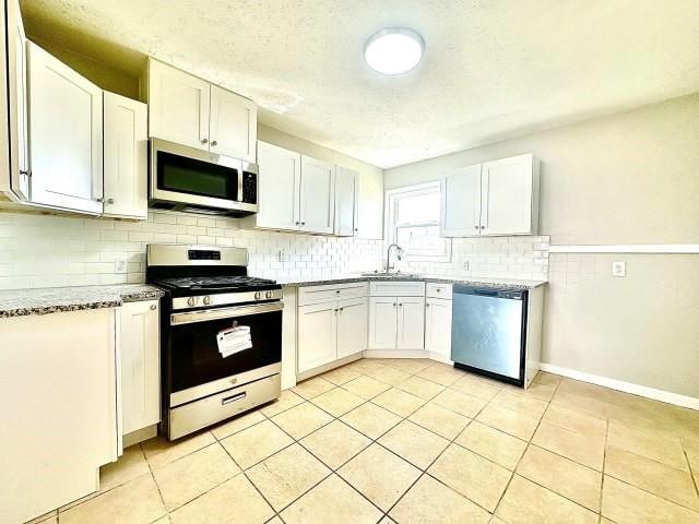 kitchen with appliances with stainless steel finishes, a sink, and white cabinetry