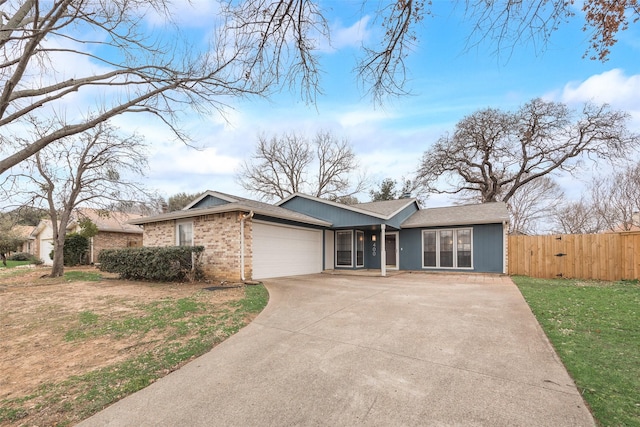 view of front of home with a garage, concrete driveway, brick siding, and fence