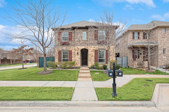 view of front of house with stone siding, brick siding, fence, and a front lawn