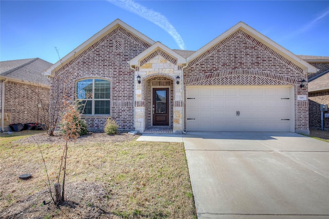 french country home featuring an attached garage, stone siding, driveway, and brick siding