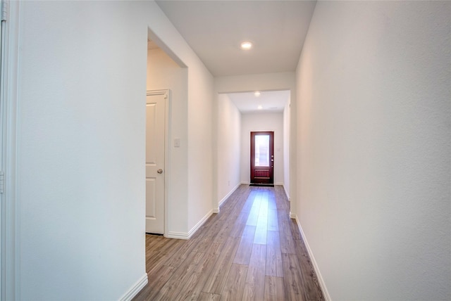 corridor featuring wood finished floors and baseboards