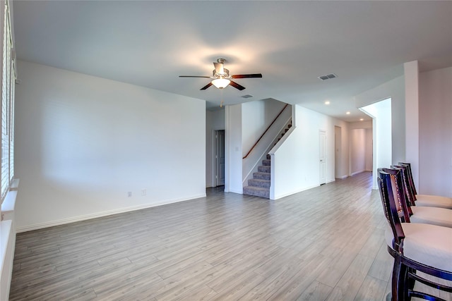 living room featuring visible vents, wood finished floors, stairway, baseboards, and ceiling fan