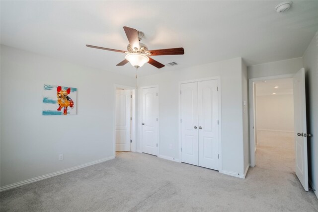 unfurnished bedroom featuring baseboards, ceiling fan, visible vents, and light colored carpet