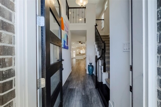 entryway featuring dark wood-style floors, stairway, and a towering ceiling