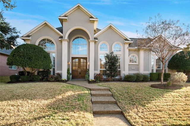 mediterranean / spanish house featuring stucco siding, a front yard, and french doors