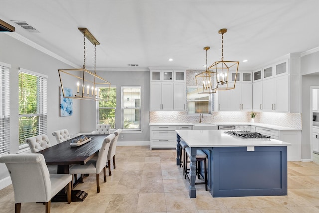 kitchen with white cabinets, a kitchen island, glass insert cabinets, stainless steel appliances, and pendant lighting