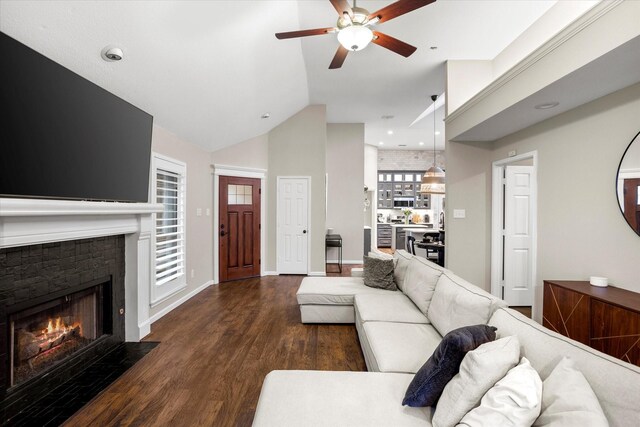 living area with high vaulted ceiling, a fireplace with flush hearth, a ceiling fan, baseboards, and dark wood-style floors