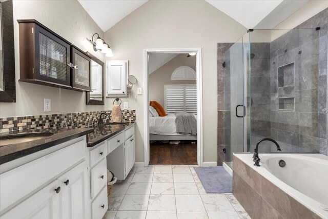 ensuite bathroom with lofted ceiling, marble finish floor, a sink, and ensuite bath