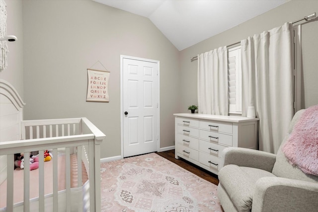 bedroom with a nursery area, baseboards, vaulted ceiling, and light wood finished floors