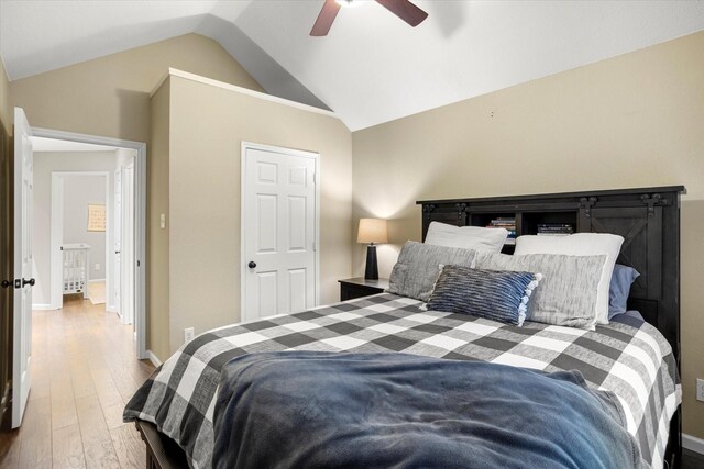 bedroom with light wood-type flooring, lofted ceiling, baseboards, and a ceiling fan