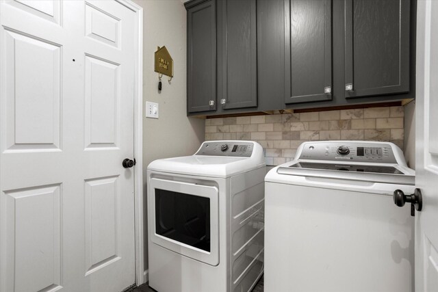 clothes washing area with independent washer and dryer and cabinet space