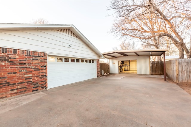 view of property exterior with a garage, brick siding, an outbuilding, and fence