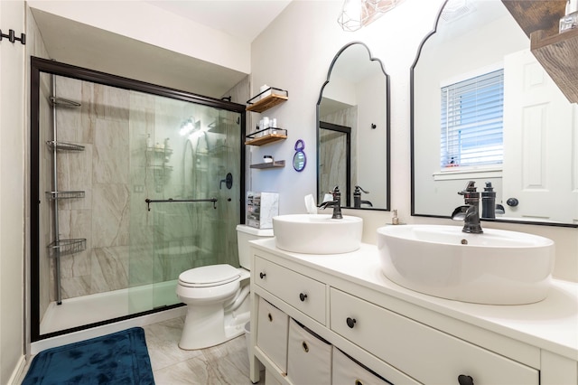 bathroom featuring toilet, a stall shower, double vanity, and a sink