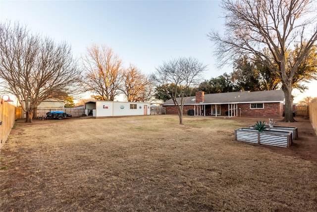 yard at dusk featuring a fenced backyard and a vegetable garden