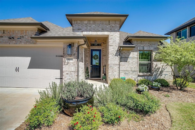 view of front facade with an attached garage, driveway, a shingled roof, and stone siding