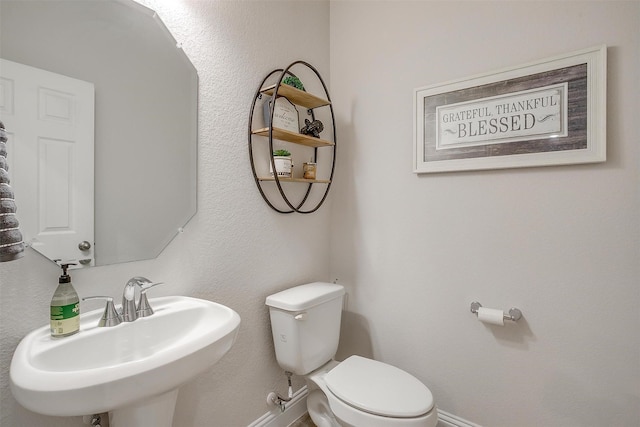bathroom with baseboards, a sink, and toilet