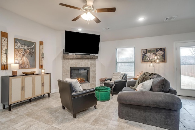 living area with visible vents, ceiling fan, light tile patterned flooring, and a tile fireplace