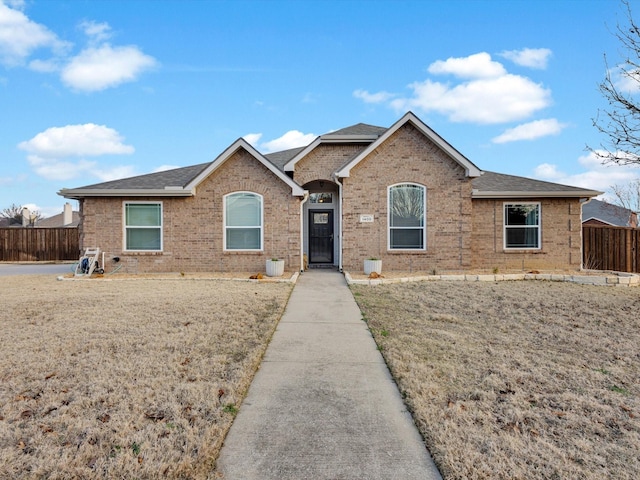 ranch-style home with brick siding, a shingled roof, and fence