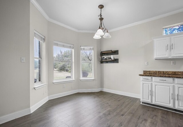 unfurnished dining area with ornamental molding, dark wood-style flooring, and baseboards