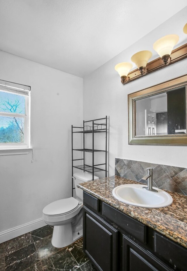 bathroom featuring toilet, baseboards, and vanity