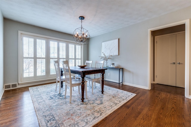 dining room with dark wood-style floors, a chandelier, visible vents, and baseboards