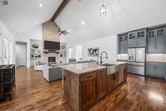 kitchen featuring stainless steel appliances, a sink, visible vents, open floor plan, and glass insert cabinets