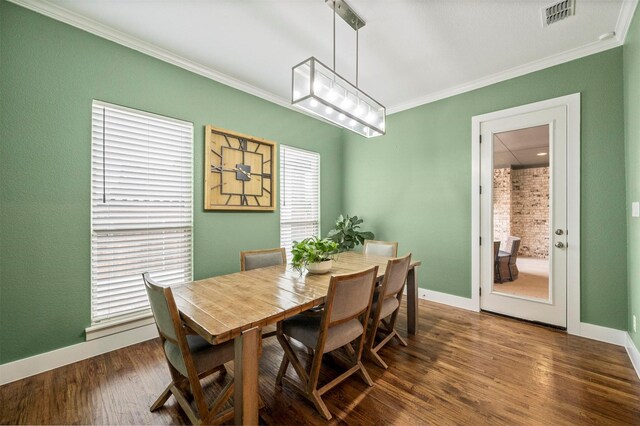 dining space with dark wood-type flooring, visible vents, crown molding, and baseboards