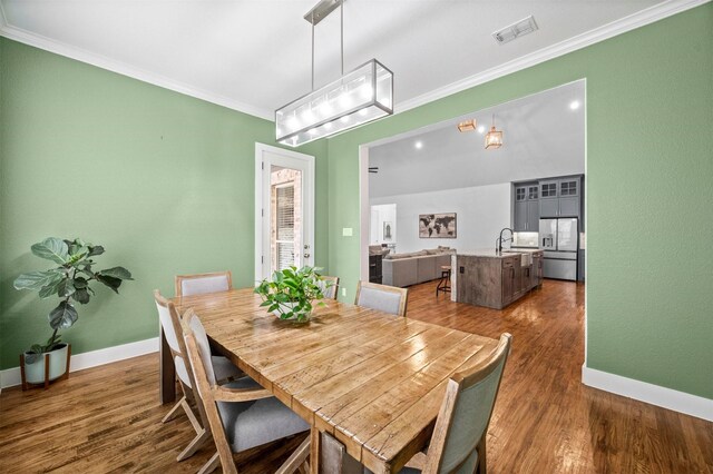 dining area featuring dark wood-style floors, baseboards, visible vents, and crown molding