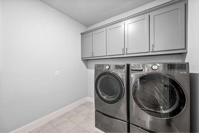 laundry area featuring cabinet space, baseboards, separate washer and dryer, and light tile patterned flooring