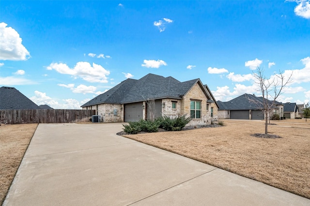 french country home with central AC, fence, a garage, stone siding, and driveway