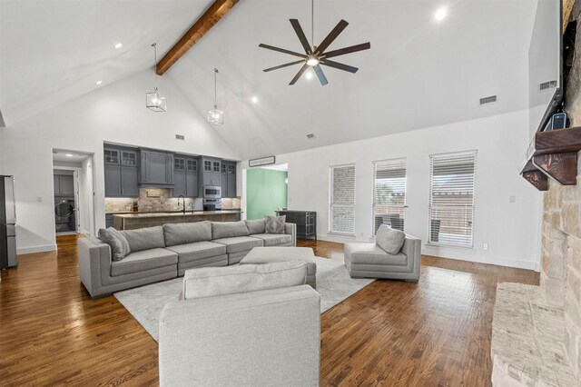 living room featuring dark wood-type flooring, beam ceiling, visible vents, and high vaulted ceiling