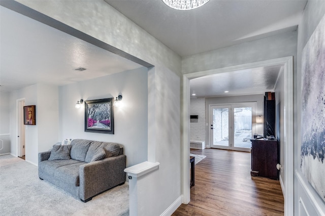 living area featuring french doors, wood finished floors, visible vents, and baseboards