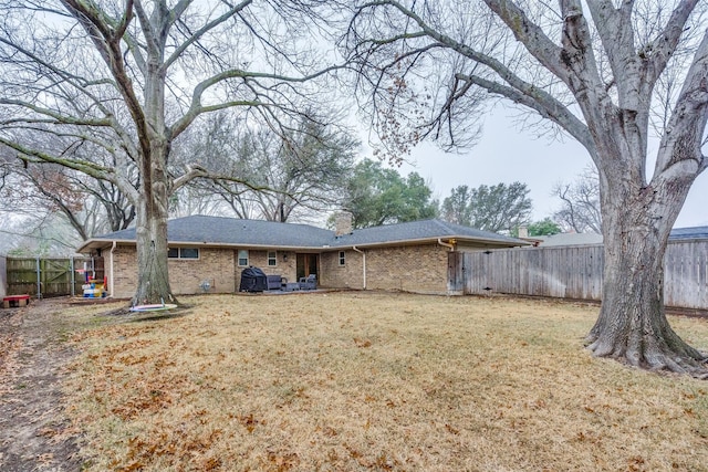 back of house featuring brick siding, a yard, a chimney, and a fenced backyard