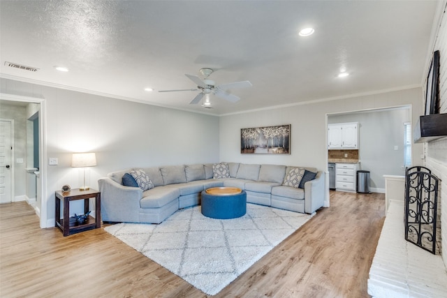 living room featuring ceiling fan, recessed lighting, visible vents, light wood-style floors, and crown molding