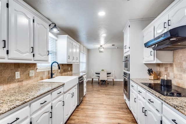 kitchen featuring white cabinets, a sink, light wood-type flooring, black electric cooktop, and exhaust hood