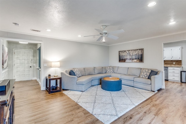 living area featuring light wood-style floors, visible vents, ornamental molding, and a ceiling fan