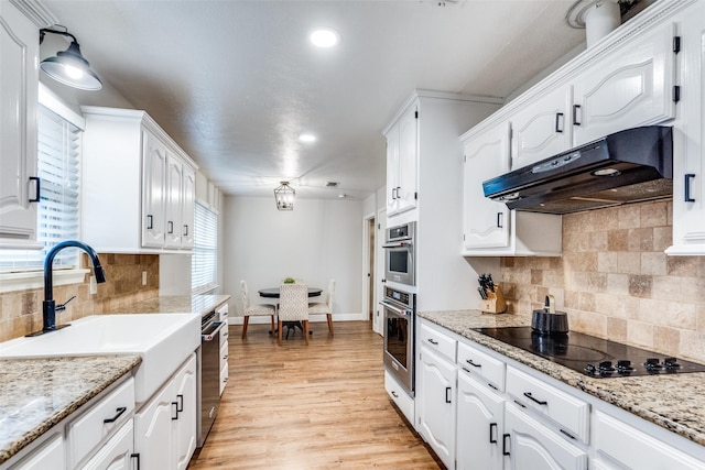 kitchen with under cabinet range hood, appliances with stainless steel finishes, white cabinets, and a sink