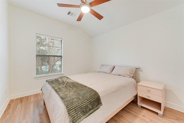 bedroom with lofted ceiling, visible vents, light wood-style floors, ceiling fan, and baseboards