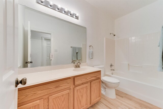 full bath featuring toilet, tub / shower combination, wood finished floors, and vanity