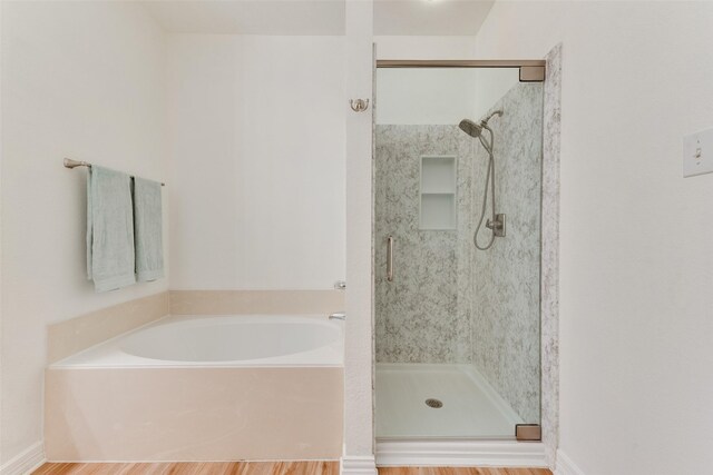 bathroom featuring a stall shower, a garden tub, and wood finished floors