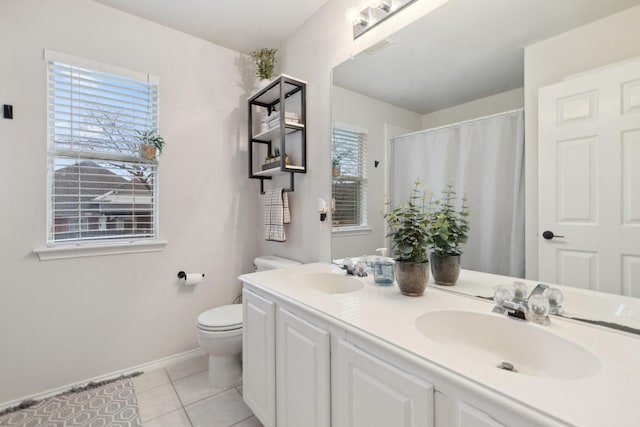 bathroom with double vanity, a sink, toilet, and tile patterned floors