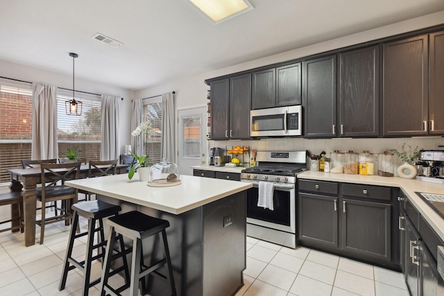 kitchen featuring stainless steel appliances, hanging light fixtures, light countertops, and visible vents