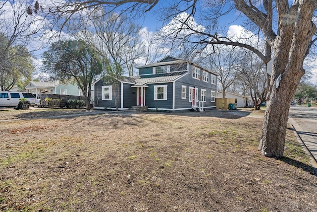 view of front of property featuring entry steps, a standing seam roof, a front lawn, and metal roof