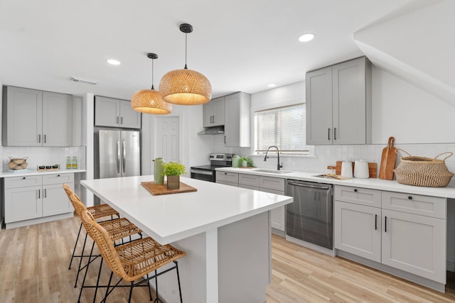 kitchen with a breakfast bar area, light countertops, appliances with stainless steel finishes, a kitchen island, and a sink