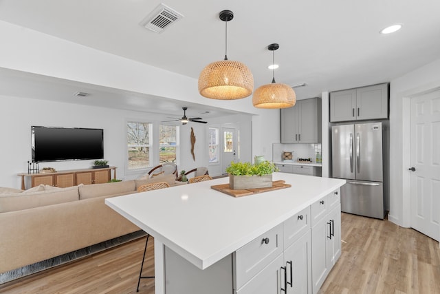 kitchen featuring a kitchen island, a kitchen breakfast bar, open floor plan, light countertops, and freestanding refrigerator