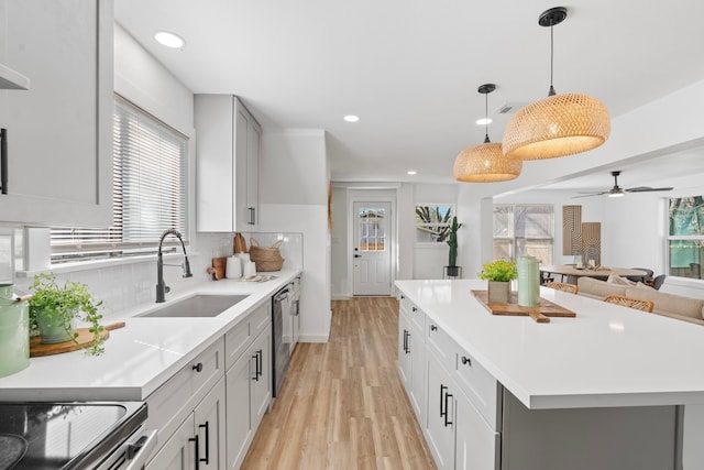 kitchen featuring open floor plan, a center island, hanging light fixtures, light countertops, and a sink