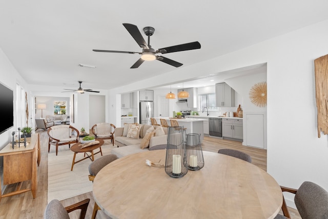 dining space with ceiling fan and light wood-type flooring